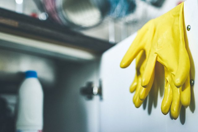 a pair of rubber gloves hanging over a door underneath a kitchen sink at home