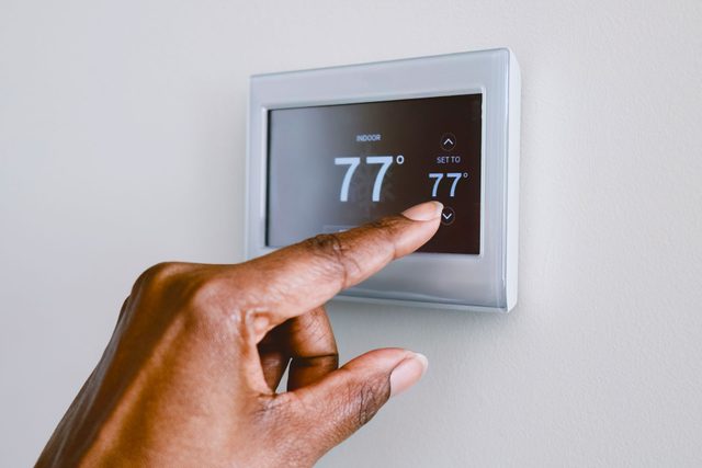 Close-up of unrecognizable black woman adjusting thermostat