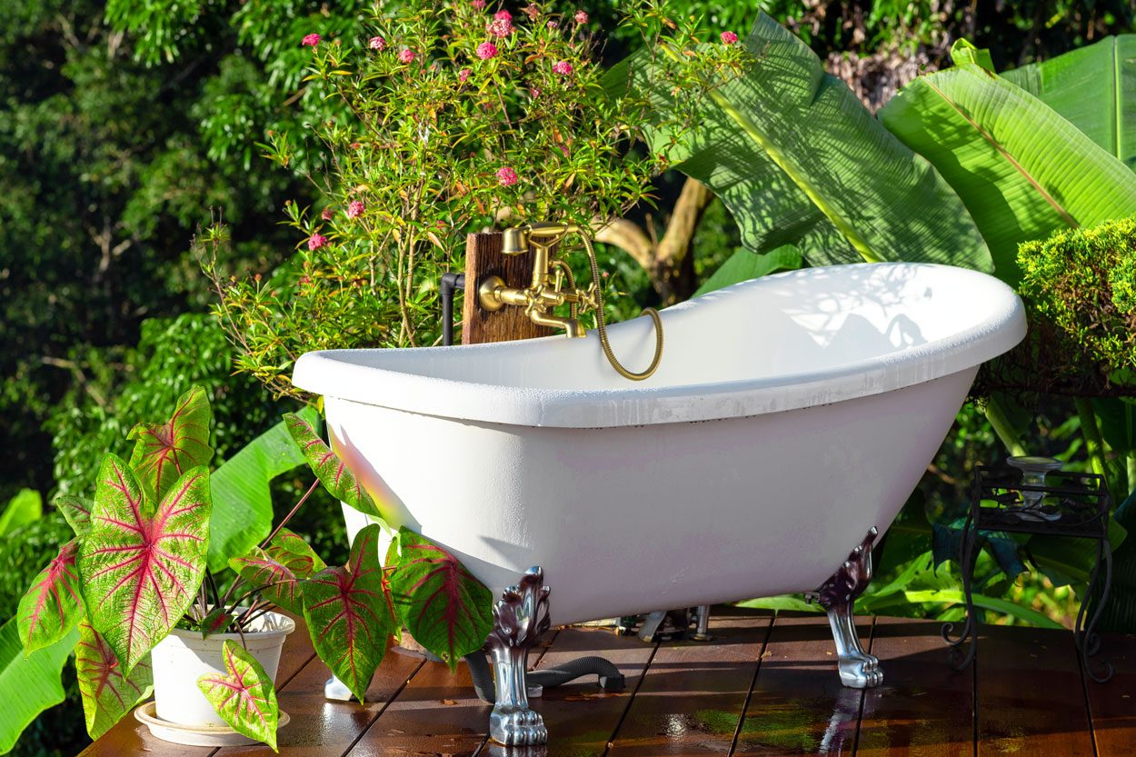 Outdoor Bathtub With Relaxing Natural Scene on an outdoor deck surrounded by plants and greenery