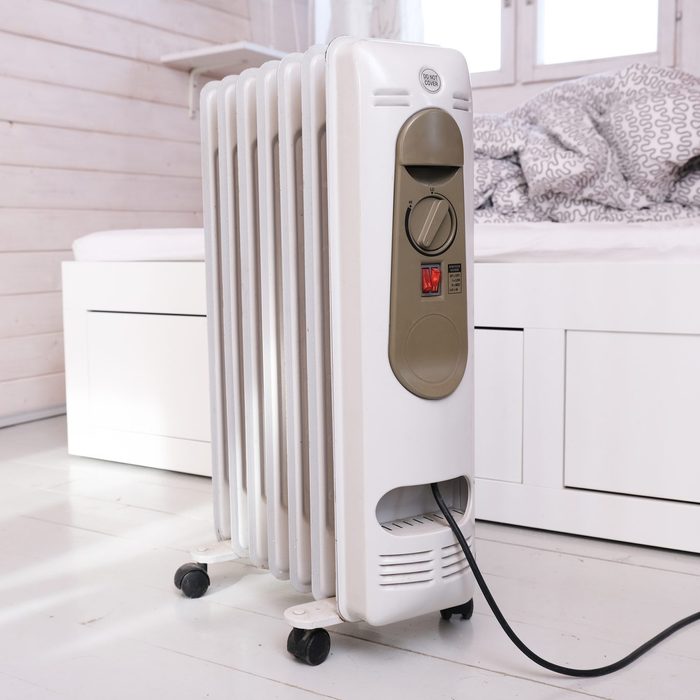 Oil-filled electrical mobile radiator heater for home heating and comfort control in the room in a wooden country house