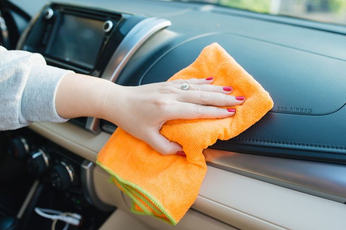 Hand With Microfiber Cloth Cleaning Dashboard of Car or Unknown SUV