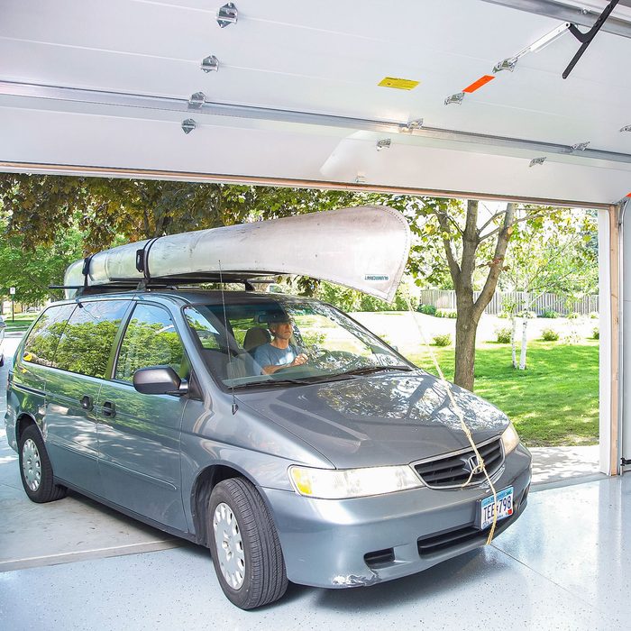A Car with Kayak Loaded on Top enters through Tall Garage Doors