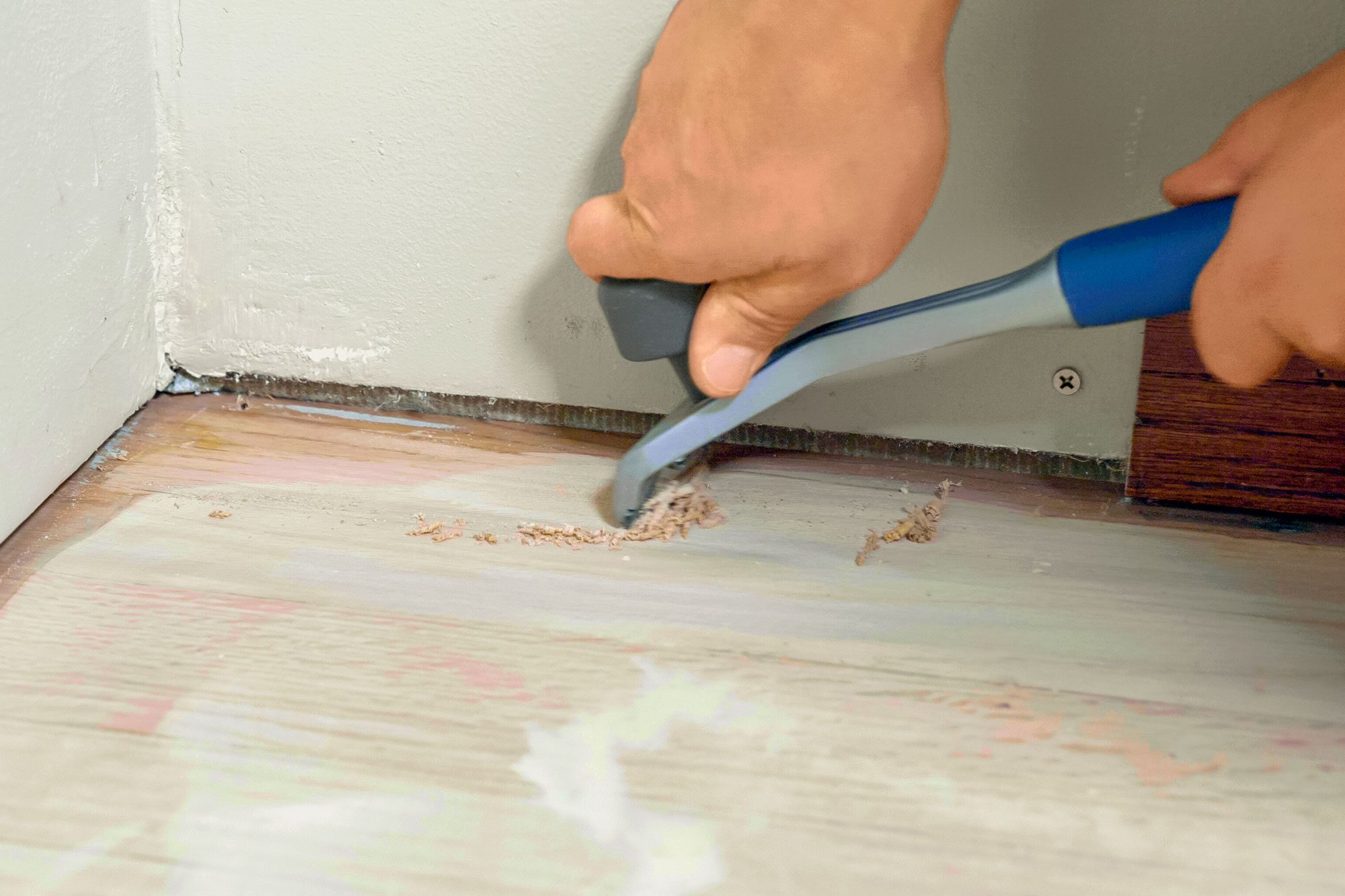 Scraping Corners of Wooden Floor with Carbide Paint Scraper