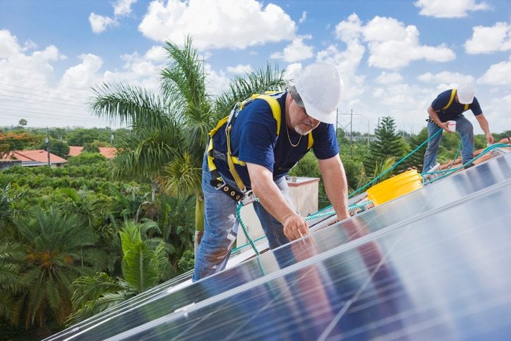 Two men installing solar panels on residential home roof