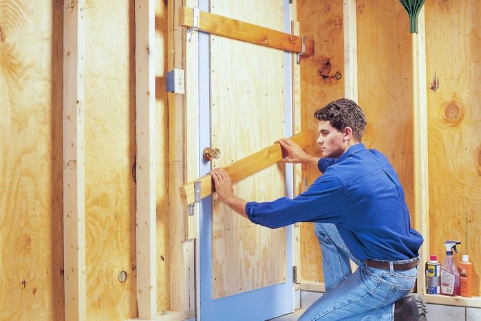 man adding Plywood Reinforcement to a Wooden Garage Entry Door
