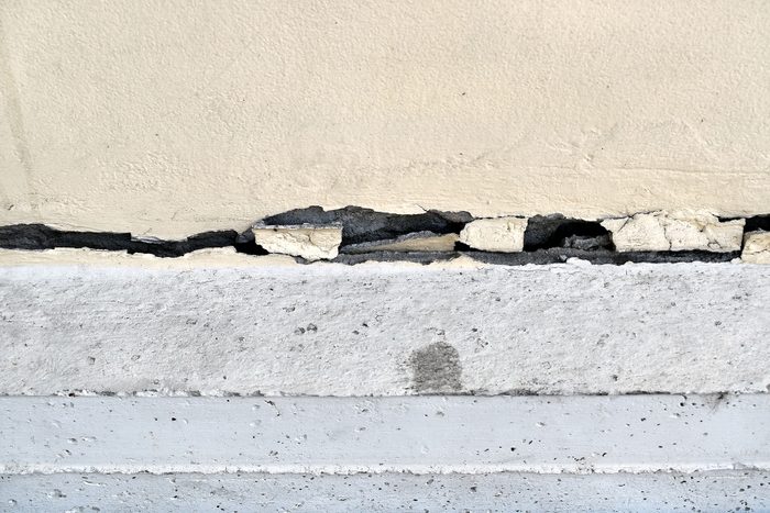 Large cracks are long crooked line on base of siding wall 