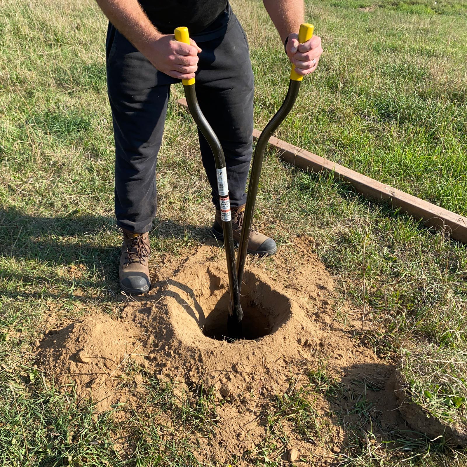 cleaning hole using a hand-operated clamshell post hole digger.