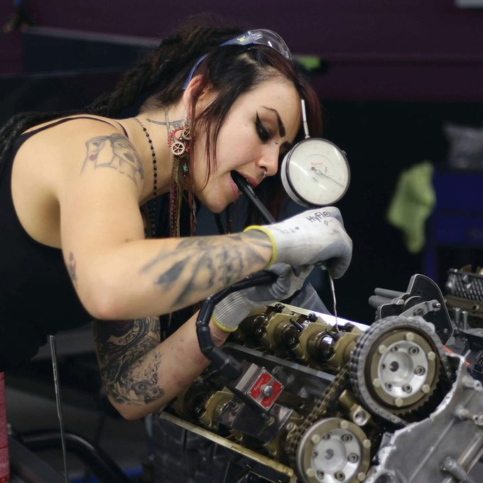 Girl repairing the engine of a car