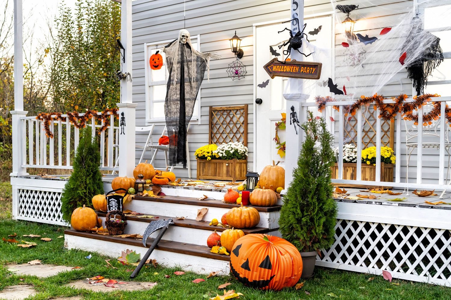 Well Lit Front Porch with Halloween Decorations such as Pumpkins, Bats, Garland, and assorted Fall Floral