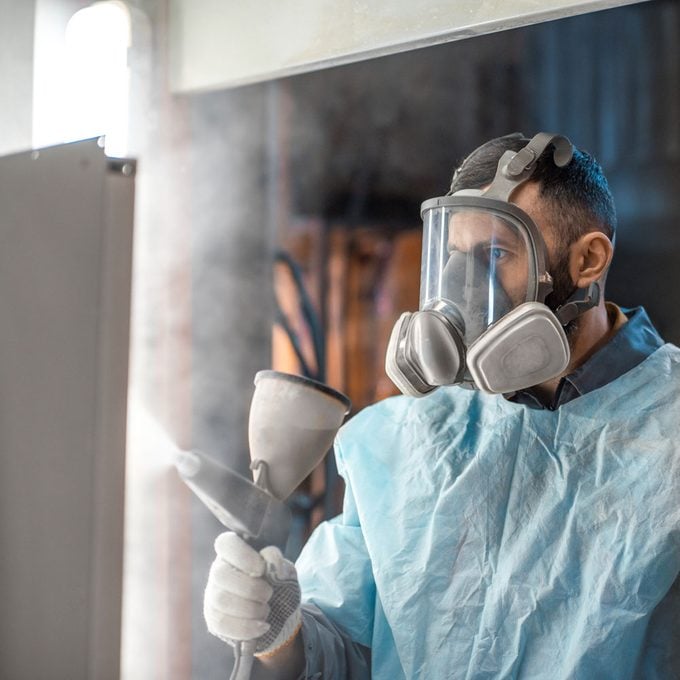 Painter in Protective Gear Paints Metal Products With Powder Coating Paint Gun