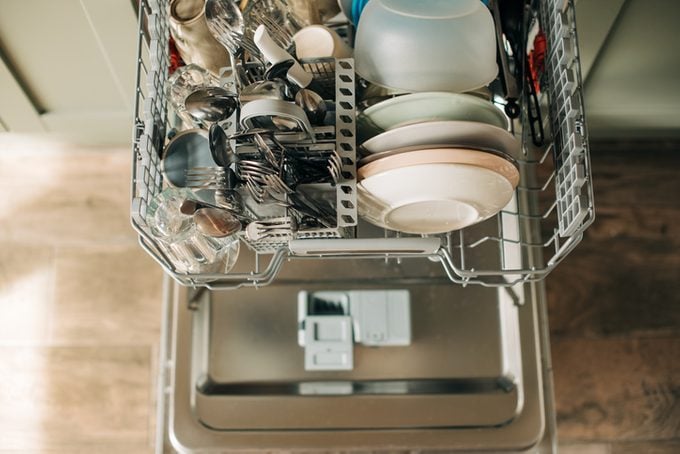 Open dishwasher with clean dishes in the white kitchen