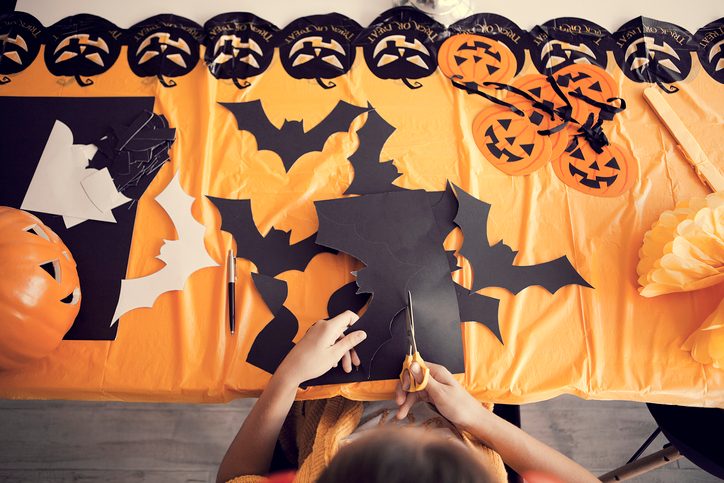Making Halloween decorations by cutting bats and pumpkins out of colorful construction paper