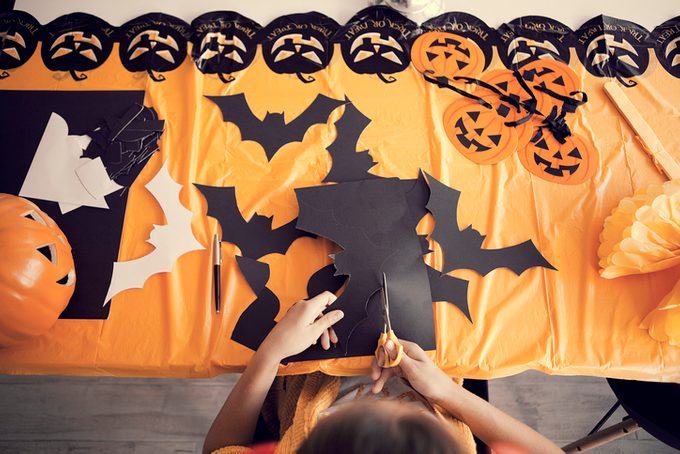Making Halloween decorations by cutting bats and pumpkins out of colorful construction paper