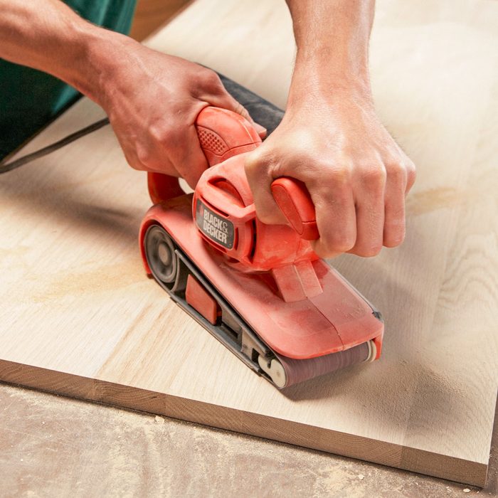 A Man Sanding Wood With Sander