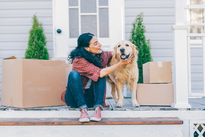 Мid Adult Woman Moving To New House And Sitting On The Stairs And Petting Her Golden Retriever