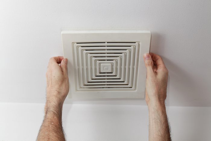 Man's Hands Removes Air Duct Cover From the Ceiling for Proper Cleaning and Maintenance