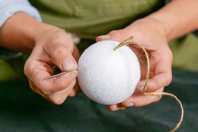 threading twine into foam ball with an embroidery needle
