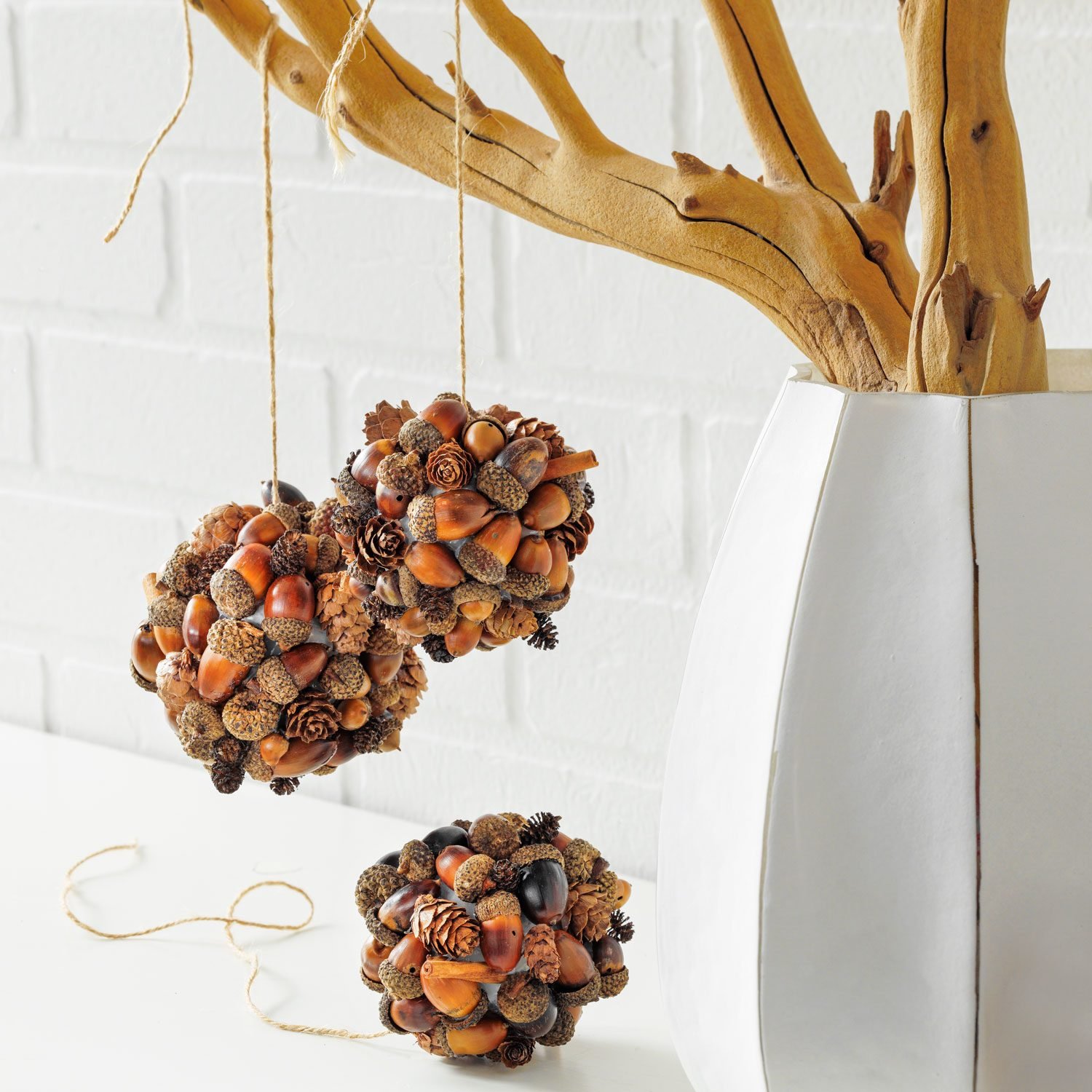 Acorn Baubles Hanging on a Painted Branch in a Fancy White Vace