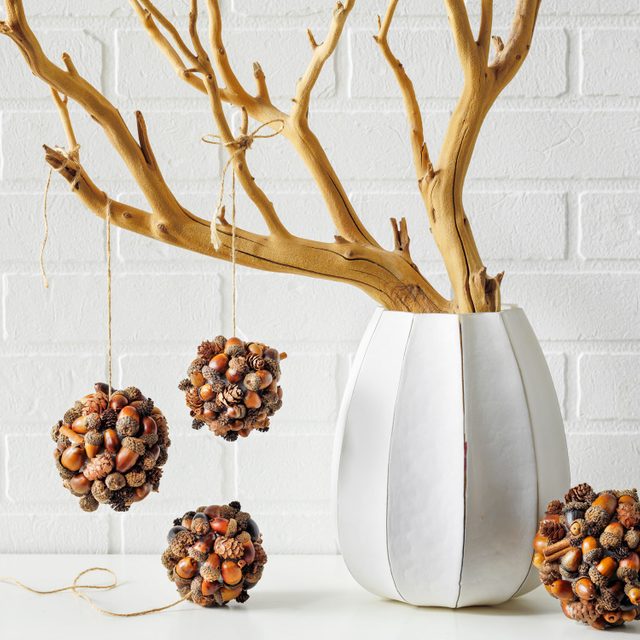 Acorn Baubles Hanging on a Painted Branch in a Fancy White Vace