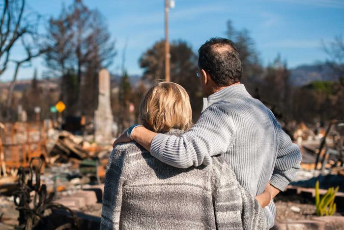 Man and his wife owners, checking burned and ruined house and yard after fire, consequences of fire disaster accident. Ruins after fire disaster.
