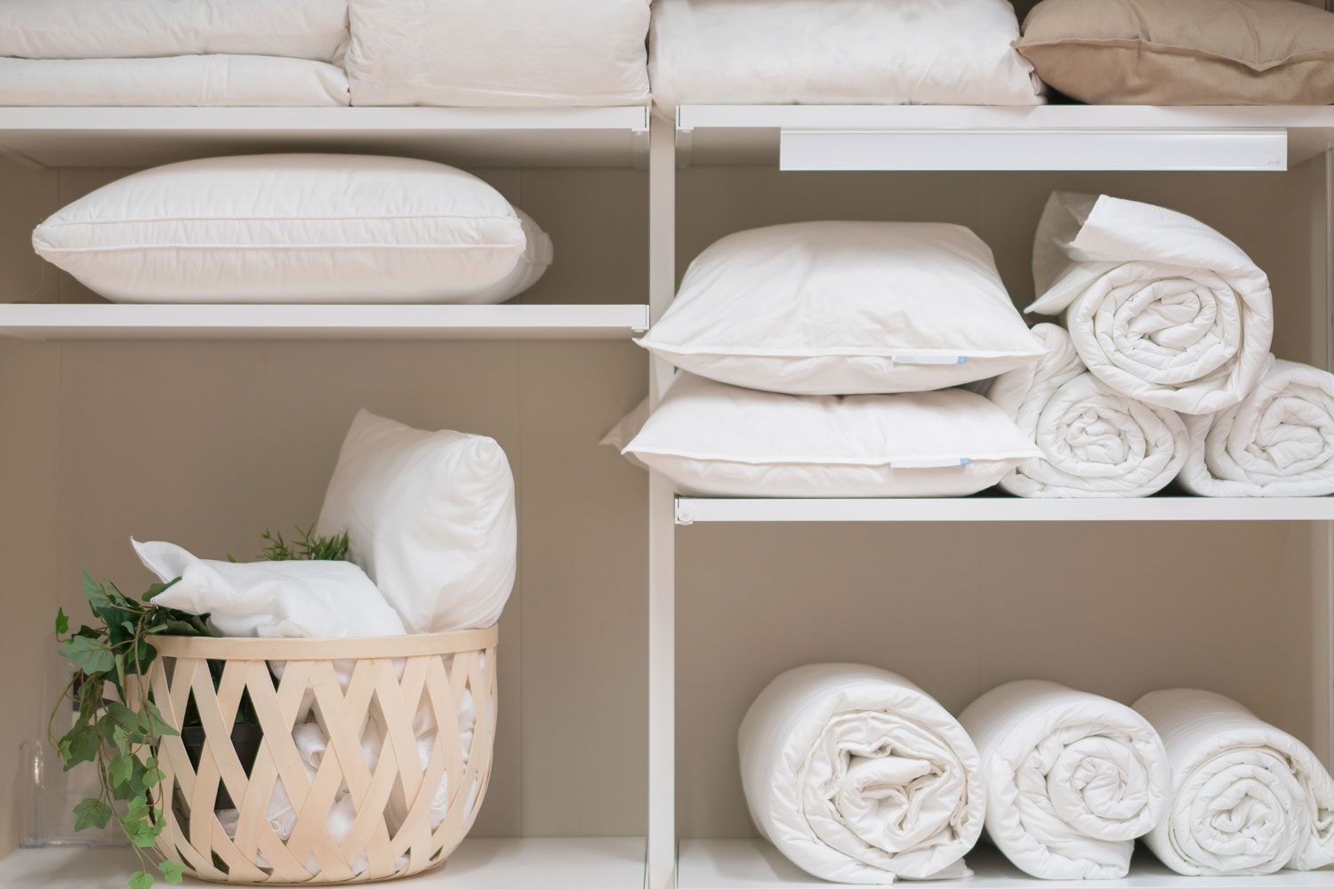 Various Household Items Such As Pillows And Quilts Standing In The White Cupboard of the laundry room