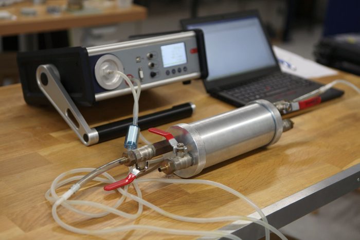 Dosimetrist holding a portable gamma radiation dosimeter set on a long tube with sample