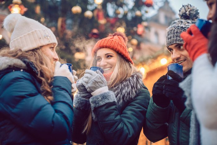 Group Of Friends Drinking Mulled Wine In The Cold at A Christmas Market