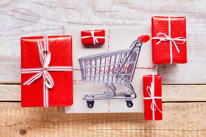 High Angle View Of A Small Shopping Cart And wrapped holiday Gifts On Wooden Table, Online Shopping for black friday, cyber monday, holiday deals