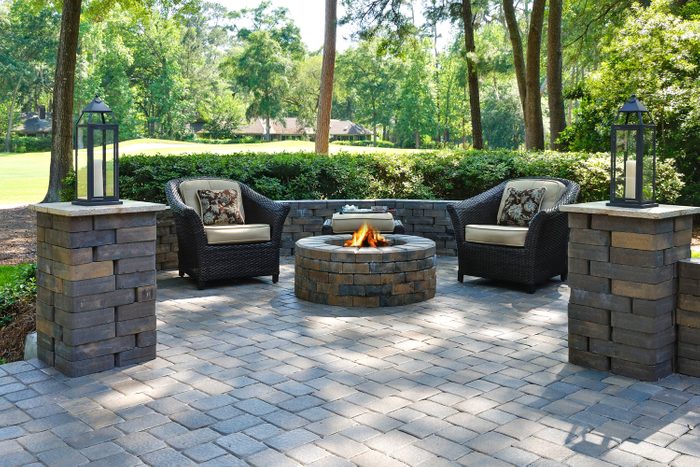 Beautiful Outdoor Patio Area with Pavers, Two Comfortable Armchairs And A Fire Pit In A Green Environment