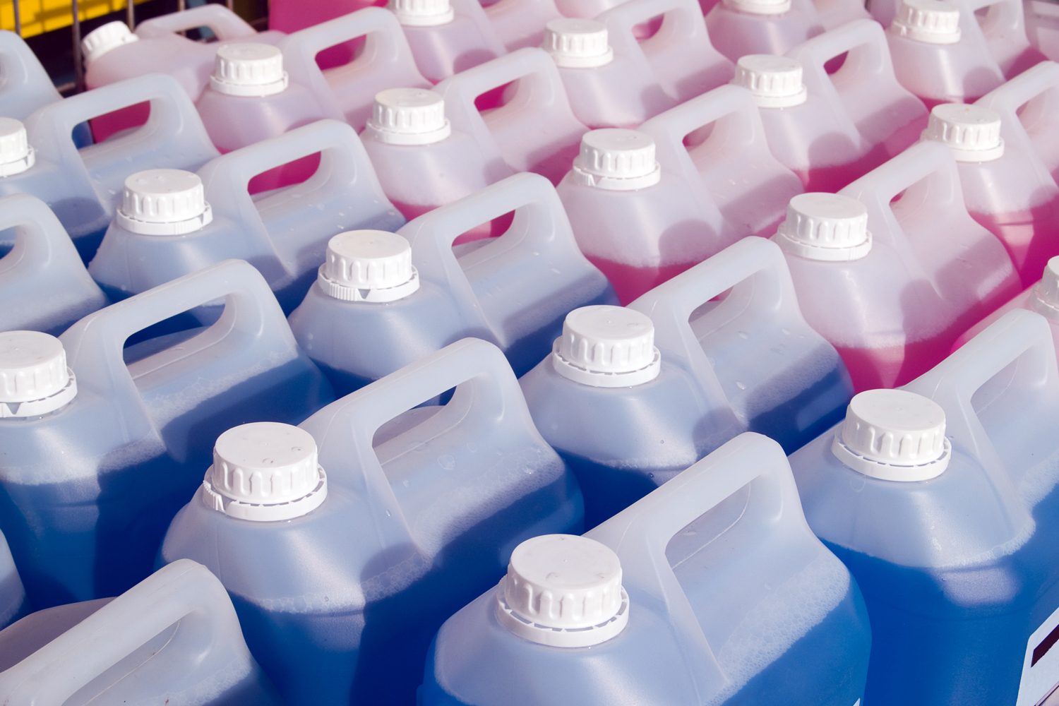 Blue and pink liquids in large plastic bottles with white caps.