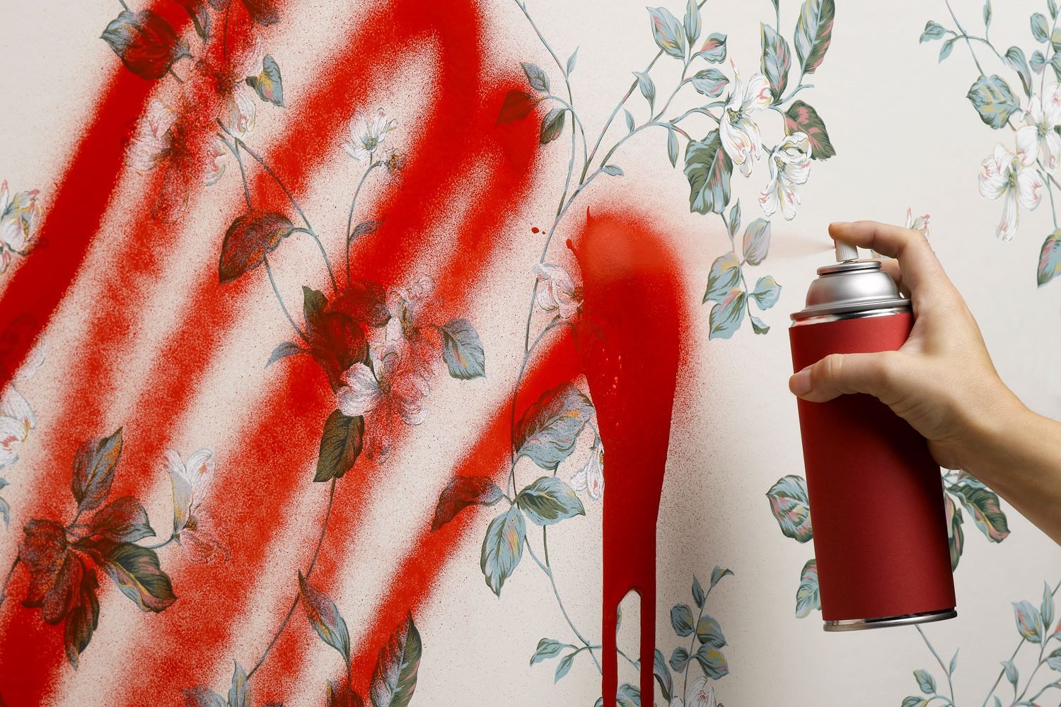 Female Hand Spray Painting floral and white Wallpaper with red spray paint can