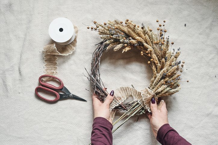Close-Up of Woman's Hands Making a beautiful autumn wreath made of dried plants for an autumn fall decoration