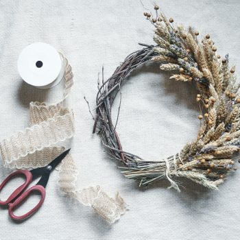 Making a Fall Autumn Wreath with Dried Up Plants, Twigs, Scissors and Ribbon to make a Decoration for a home or apartment