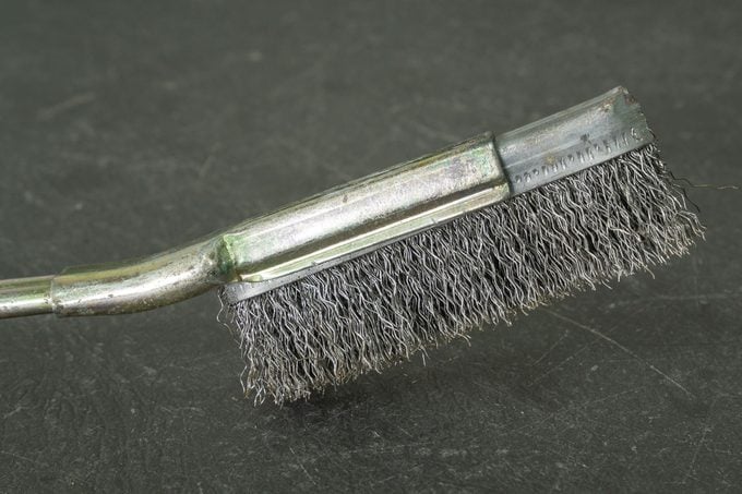 Old metal wire brush with steel handle on grey table