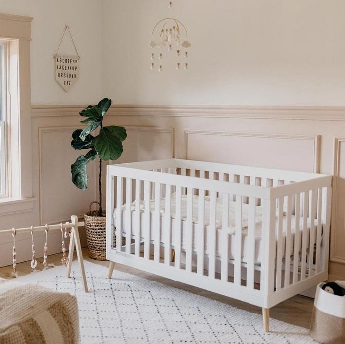 A room with baby crib with wooden furniture