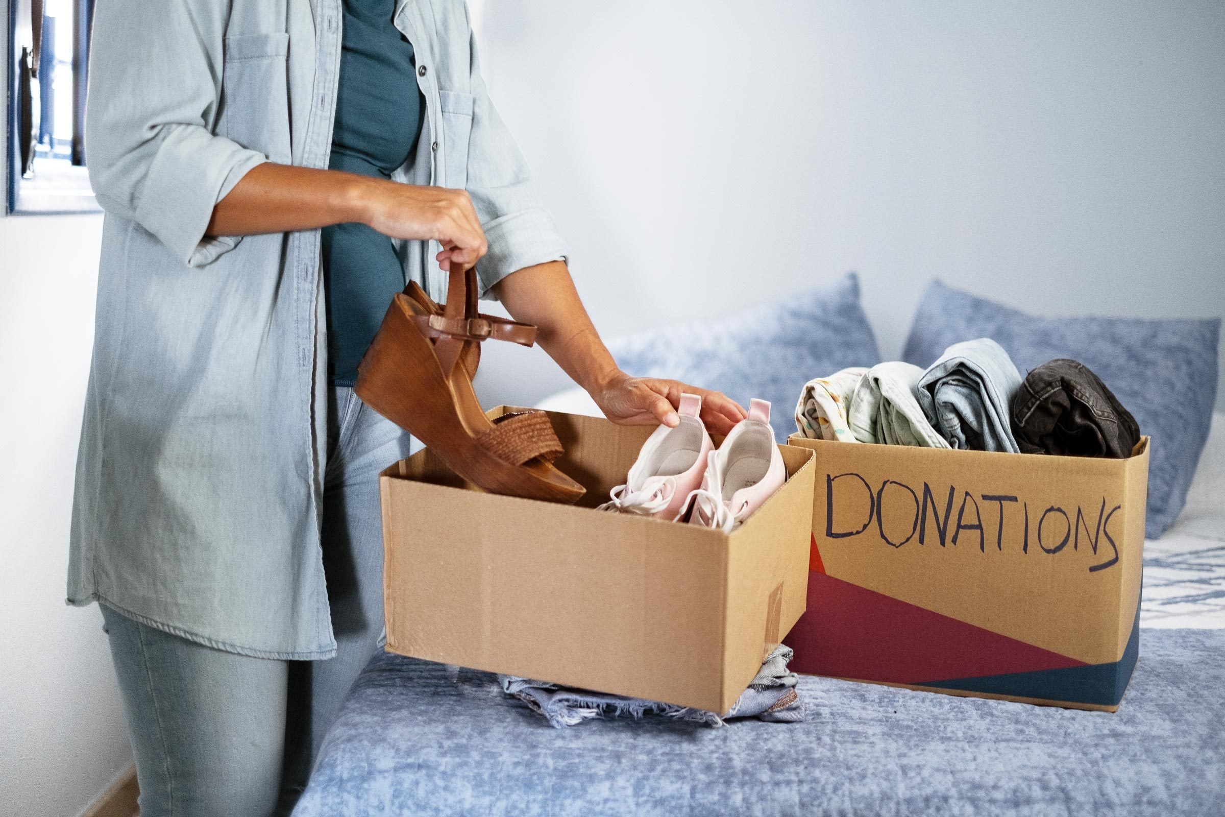 woman packing shoes and pants into cardboard donation boxes