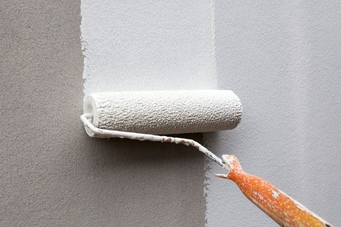 A man paints a wall with white paint