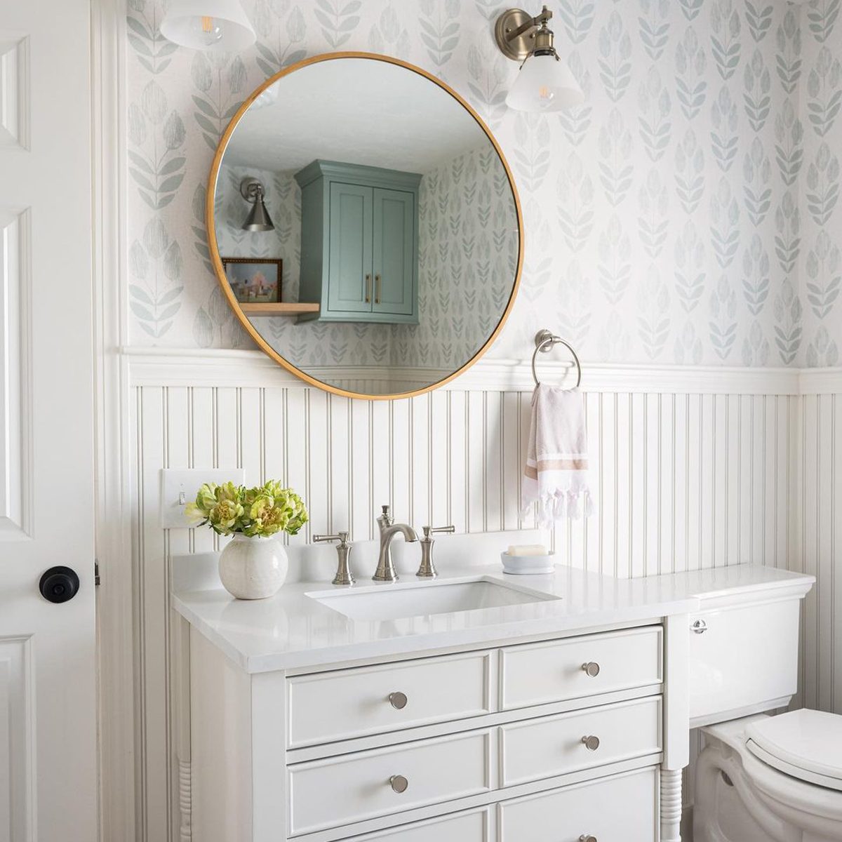an all white bathroom with a round mirror