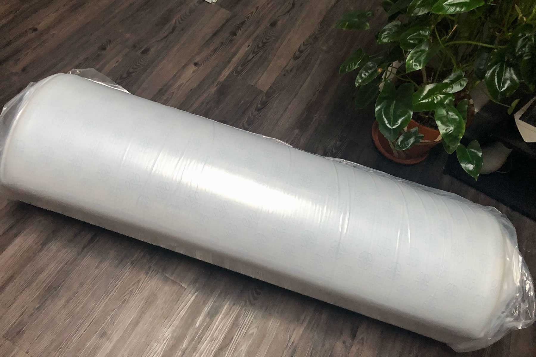 A roll of plastic wrap sitting on a wooden floor.