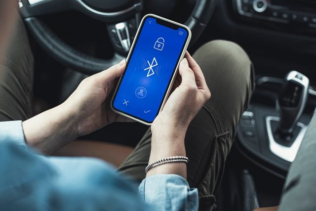 Woman accessing bluetooth on mobile phone in car