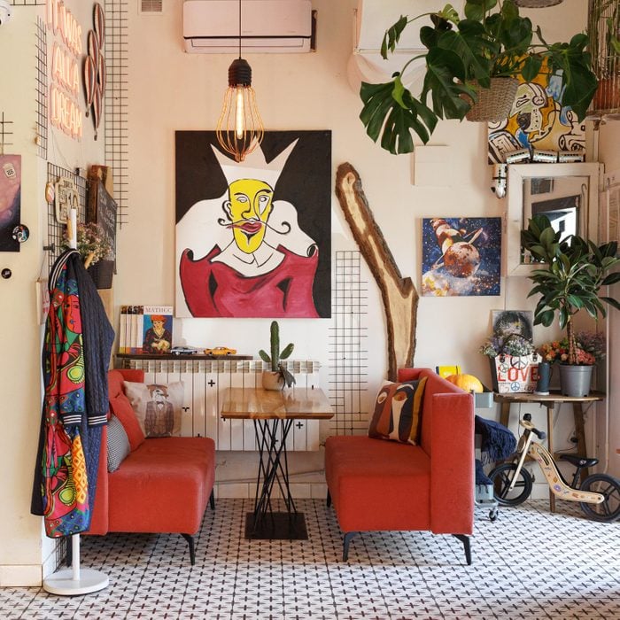 eclectic interior design dining room with two red couches around a table and lots of art on the walls
