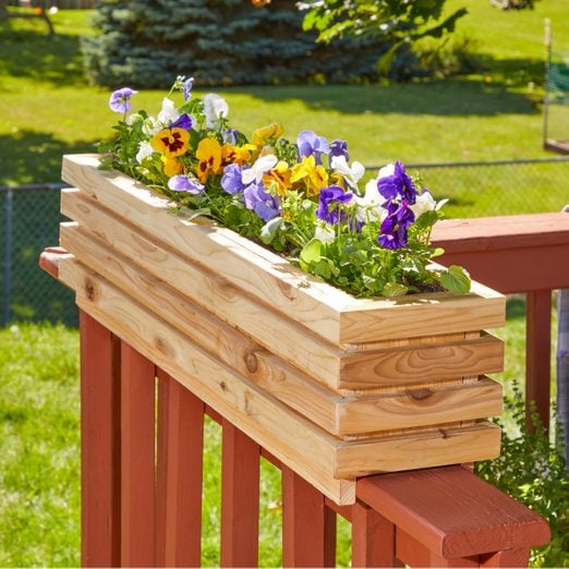 How To Build Deck Railing Planters with multicoloured flowers planted in it.