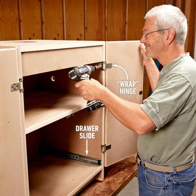 A man is using a drill to build a cabinet.
