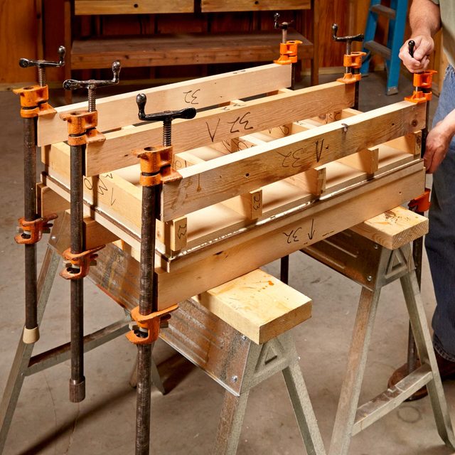 A man is working on a wooden bench in a workshop to build a cabinet.