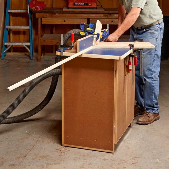A man working on a table saw in a garage.