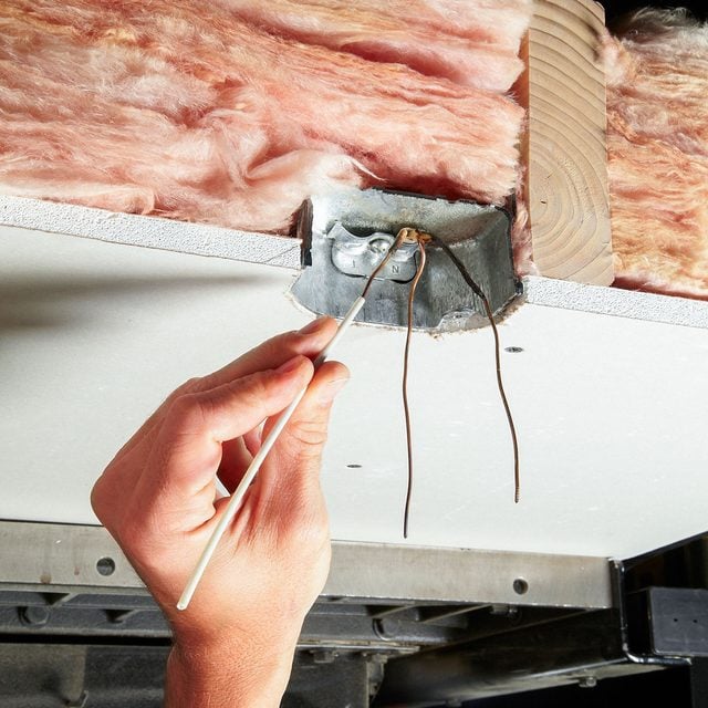 A person is putting insulation on a ceiling.