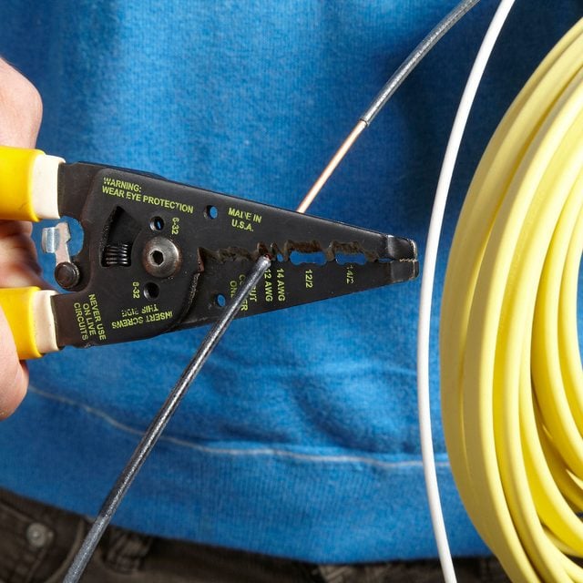 A person holding a pair of yellow wire cutters.