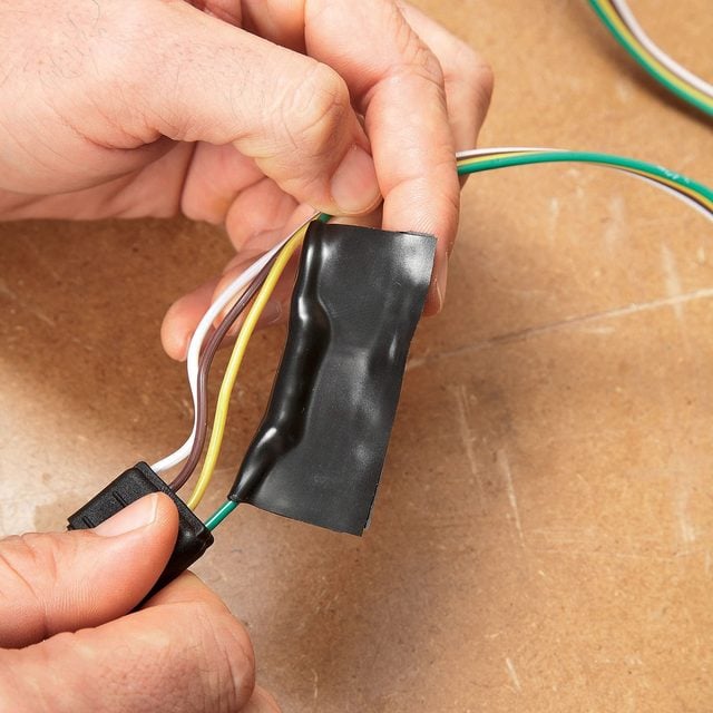 A person using black tape to connect wire