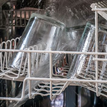 Open Dishwasher Machine Spraying Water On Drinking Glass