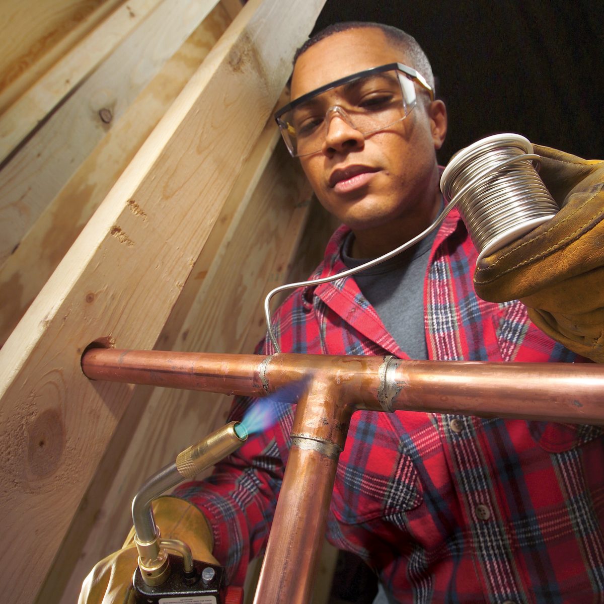 A man using a torch for welding a copper pipe